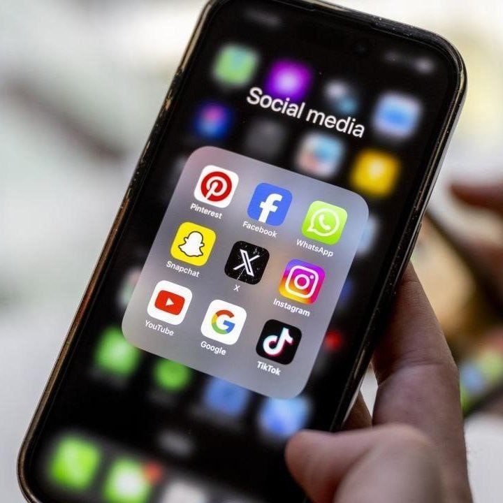 A phone with a blurred social feed beside a small paper shield